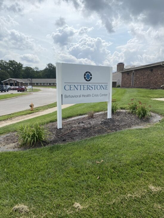 Centerstone Behavioral Health Crisis Center sign beside a landscaped lawn and brick building.