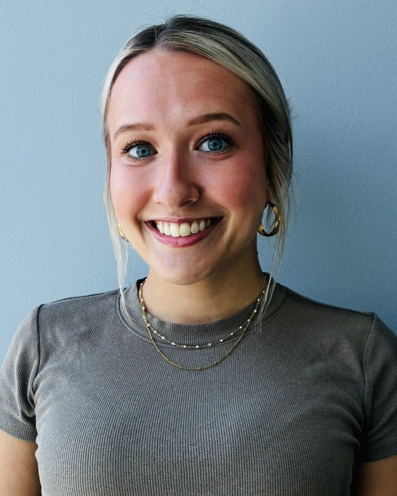 Portrait of Lauren Hoover smiling against a light blue wall.