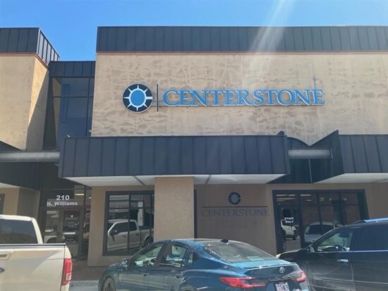 Centerstone sign above the entrance of a tan commercial building, with parked vehicles in front.