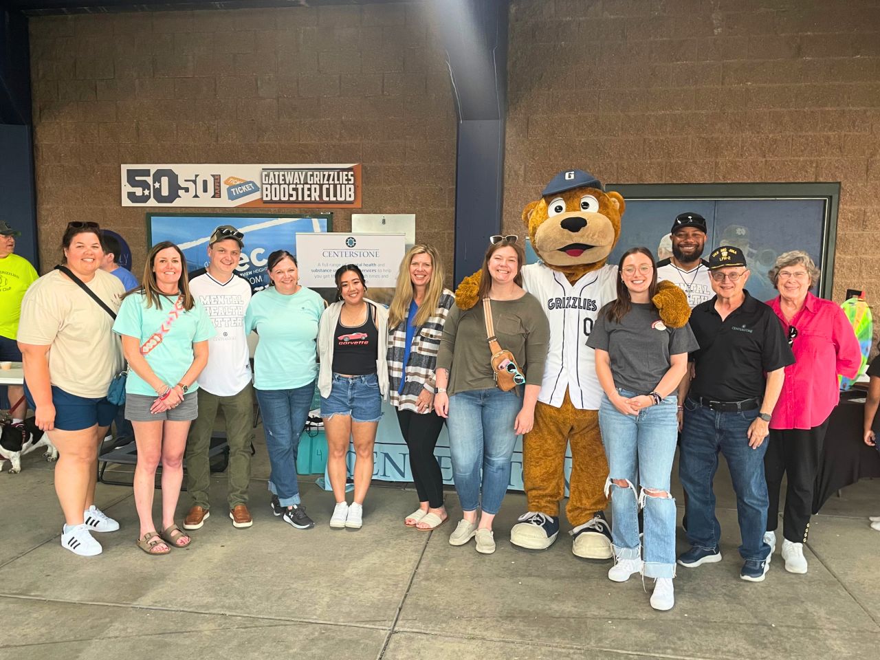 Staff at Grizzlies Game Centerstone staff posing with the Grizzlies mascott at a baseball game.