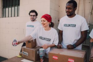 three people standing behind table with medical supplies wearing volunteer shirts
